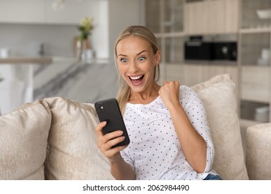 Overjoyed sincere young woman holding telephone, feeling festive getting online lottery win notification, celebrating internet success giveaway betting auction win alone at home, reaction of happiness - Shutterstock ID 2062984490