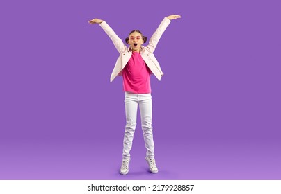 Overjoyed Teen Girl Child Isolated On Violet Studio Background Have Fun Jumping And Laughing. Smiling Teenage Kid In Casual Wear Show Height Excited About Being Tall. Childhood Growing Up.