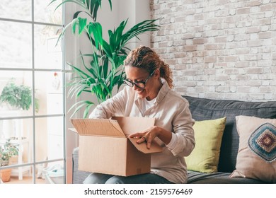 Overjoyed woman seated on sofa hold on lap small cardboard box open parcel client feels satisfied bought goods in internet, happy addressee received package from friend, quick delivery service concept - Shutterstock ID 2159576469