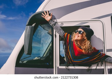 Overjoyed young adult woman oustretching arms outside the windows of a camper van and celebrate freedom and summer holiday travel vacation lifestyle