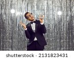 Overjoyed young African American man in formal suit sing in microphone have fun in nightclub. Smiling black guy relax rest enjoy karaoke in disco club. Entertainment and hobby concept.