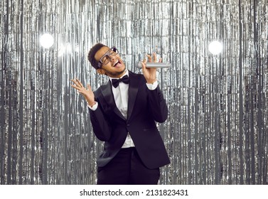 Overjoyed Young African American Man In Formal Suit Sing In Microphone Have Fun In Nightclub. Smiling Black Guy Relax Rest Enjoy Karaoke In Disco Club. Entertainment And Hobby Concept.