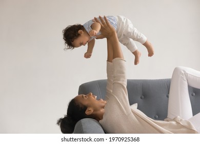 Overjoyed young African American mother relaxing on couch play with cute little toddler baby girl child. Happy mom have fun rest enjoy motherhood with small ethnic daughter kid. Parenthood concept. - Powered by Shutterstock