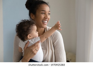 Overjoyed young African American mother hold in arms play with cute little baby daughter at home. Happy loving ethnic mom play enjoy motherhood with small toddler kid child. Parenthood concept. - Powered by Shutterstock