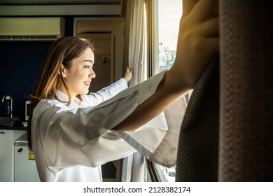 Overjoyed young beautiful woman standing by bedroom and opening curtains look in window distance meet welcome new day. Smiling female feel excited about life career opportunities or perspectives.