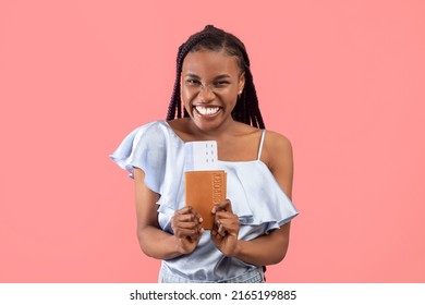 Overjoyed Young Black Woman Holding Passport And Plane Tickets, Going Vacation Overseas, Traveling Abroad Over Pink Studio Background. Tourism, Summer Holidays Concept