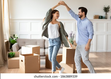 Overjoyed young Caucasian couple renters have fun excited moving in new home together. Happy man and woman tenants dance enjoy relocation day to own house. Relocation, real estate, rent concept. - Powered by Shutterstock