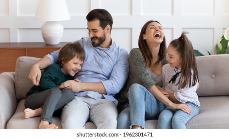 Overjoyed Young Caucasian Family With Children Have Fun Tickle Play Together In Cozy Modern Living Room. Happy Parents Feel Playful Enjoy Funny Game With Kids Relaxing Together At Home On Weekend.