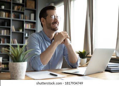 Overjoyed young Caucasian male worker sit at desk at home office distracted from computer work laughing joking. Happy millennia man using laptop have fun dreaming or thinking of job career success. - Shutterstock ID 1817934749