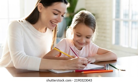 Overjoyed young Caucasian mother and little 7s daughter have fun drawing in album on family weekend together. Happy mom and small girl child engaged in funny activity paining. Hobby concept. - Powered by Shutterstock