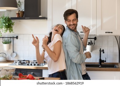 Overjoyed Young Family Having Fun In Modern Kitchen, Dancing And Laughing, Happy Young Wife And Husband Moving To Favorite Music, Enjoying Leisure Time, Cooking Dinner Together, Romantic Date