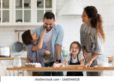 Overjoyed young family with little preschooler kids have fun cooking baking pastry or pie at home together, happy smiling parents enjoy weekend play with small children doing bakery cooking in kitchen - Shutterstock ID 1660546018