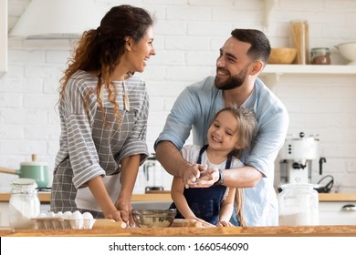 Overjoyed young family with little preschooler daughter have fun doing bakery in kitchen together, happy parents enjoy weekend with small girl child baking biscuits pastries, making pie at home - Shutterstock ID 1660546090