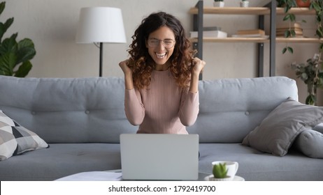Overjoyed young female in glasses look at laptop screen feel euphoric with online lottery win or success, excited woman in eyewear triumph read pleasant good news in email on computer, luck concept