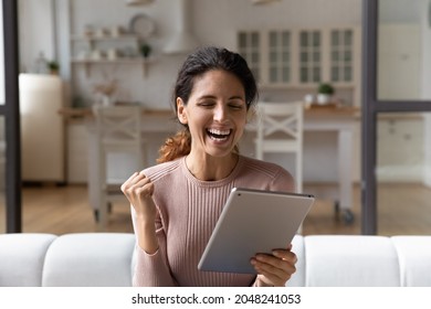 Overjoyed young female look at tablet screen triumph with promotion or hiring message on gadget. Smiling Caucasian woman use pad device feel euphoric with good news online. Success concept.
