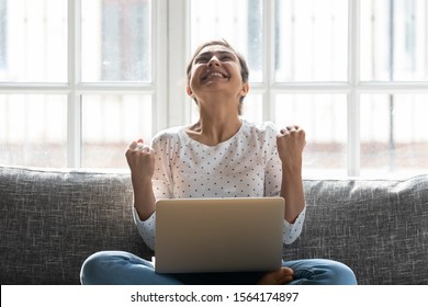 Overjoyed Young Indian Woman Celebrating Personal Achievement, Sitting With Computer On Couch At Home. Happy Euphoric Millennial Girl Getting Grant University Scholarship Or Employment Notification.