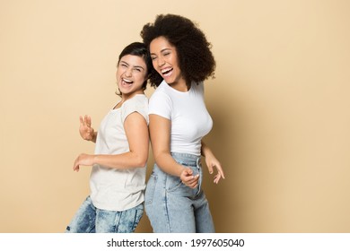 Overjoyed young multiethnic girlfriends isolated on yellow studio background dance have fun together. Smiling happy millennial diverse female friends laugh entertain. Diversity, humor concept. - Powered by Shutterstock