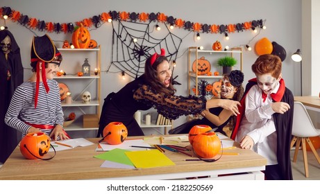 Overjoyed Young Teacher And Kids Dressed In Costumes Engaged In Learning Activity On Halloween Eve. Happy Nanny Have Fun Play With Kids Celebrate Scary All Saint Eve In School Or Kindergarten.