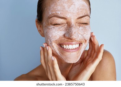 Overjoyed young woman with a freckles skin care beauty portrait.  Applying white peeling cosmetic product to whole her face. Dermatology. Exfoliating - Powered by Shutterstock