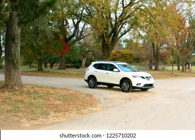 Overland Park, KS, USA, October 21 2015: A Nissan Rogue 2015 White Suv Parked On An Empty Road With Huge Trees On Both Side, During Fall Season