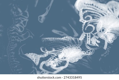 Overlapping patterns on textured fabric with intricate embroidery and decorative stitchwork create a tactile, multi-dimensional surface in soft blue hues.