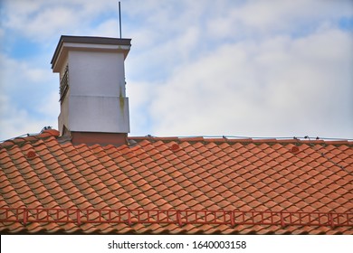 Overlapping rows of red tiles roof with chimneys in Poland, ridge tiling material regular pattern background in horizontal orientation, nobody.