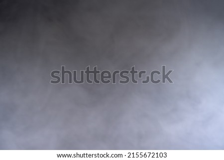 Overlay or texture: a black background getting almost filled with gray smoke. Studio shot.
