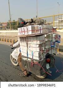 An overloaded motor bike with ride delivering cargo   - Karachi Pakistan - Jan 2021