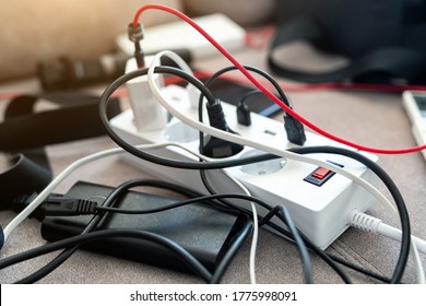 Overloaded Power Socket Plug Extendion At Home. Tangled Cords Of Home Appliances And Chargins Gadgets Mess