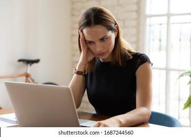 Overloaded woman sit at workplace desk touch head feels unwell suffers from headache migraine, businesswoman read unpleasant news, dismissal message, notebook broken malware, problems at work concept - Shutterstock ID 1687244560