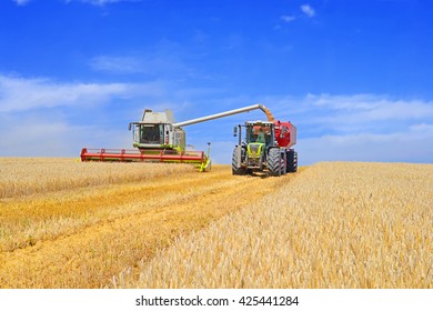 Overloading grain harvester into the grain tank of the tractor trailer - Shutterstock ID 425441284