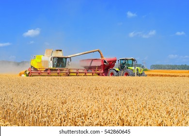 Overloading grain harvester into the grain tank of the tractor trailer - Shutterstock ID 542860645