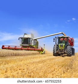 Overloading grain harvester into the grain tank of the tractor trailer - Shutterstock ID 657552253