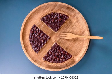 Overlook The Red Bean Pies And The Wooden 
Fork On The Round Wooden Plate With Navy Blue Background