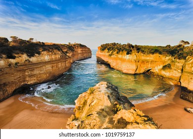 Overlooking secluded tiny Loch Ard Gorge beach in Twelve Apostles marine park on Shipwreck coast of Victoria, Australia. Warm morning light illuminates limestone cliffs and sand.