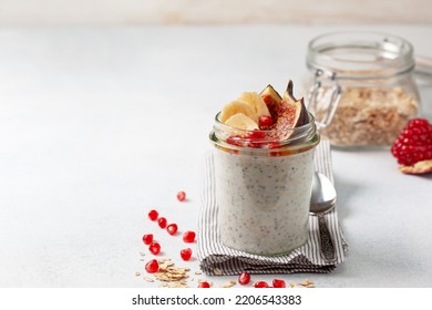 overnight oatmeal with figs, banana and pomegranate in a glass jar on a light background - Shutterstock ID 2206543383
