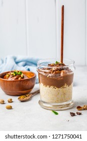 Overnight oatmeal with milk and chocolate mousse in a glass on a white background.