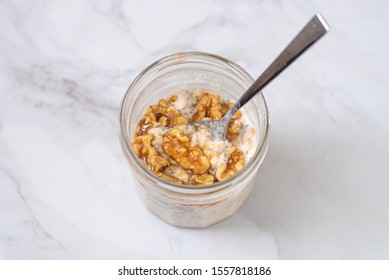 Overnight Oats With Chia Seeds, Walnuts And Yogurt, On A White Marble Background.