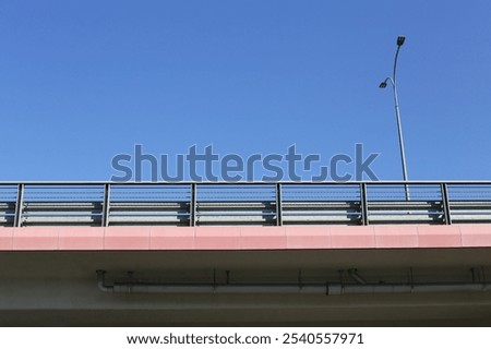 Overpass bridge with elevated road under a blue sky. Empty highway with protective barriers. Highway or bypass scene. Viaduct street landscape. City downtown. Modern transportation construction.