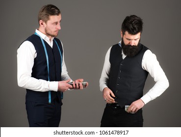 Overpayment Concept. Man With Beard Pay To Macho With Measuring Tape. Customer, Client Paying, Counting Money, Grey Background. Tailor, Greedy Designer Wants More Money For Expensive Clothes.