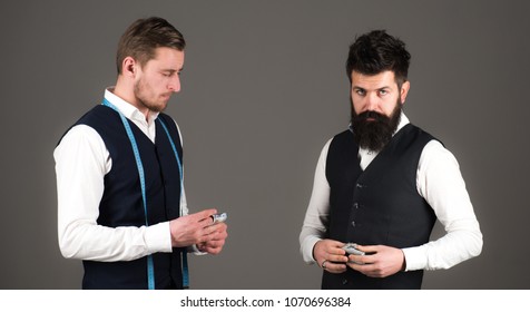 Overpayment Concept. Tailor, Greedy Designer Wants More Money For Expensive Clothes. Man With Beard Pay To Macho With Measuring Tape. Customer, Client Paying, Counting Money, Grey Background.