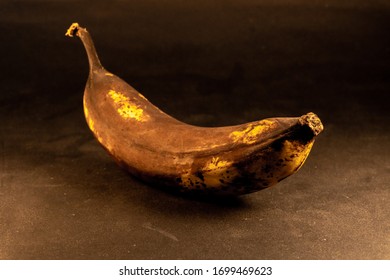 overripe dark skinned banana, lying on the dark table. - Shutterstock ID 1699469623