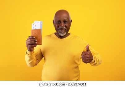 Overseas Trip. Senor Black Man Holding International Passport With Airplane Tickets And Showing Thumb Up Gesture On Orange Studio Background. Elderly Tourist With Documents Ready To Travel Abroad