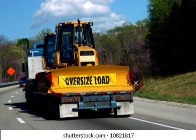 Oversize Load Of Bulldozer Is Loaded On A Flatbed Trailer Being Pulled By A Semi.  Travel Is By Interstate.