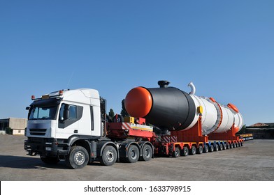 Oversize Transport Truck With Multiple Wheels And Long Storage Tank On The Tailer Parked In A Forecourt