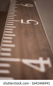 An Oversized Decorative Wooden Ruler Measures Height Upward At 4, 5, And 6 Feet On Light Colored Wood With White Hash Marks