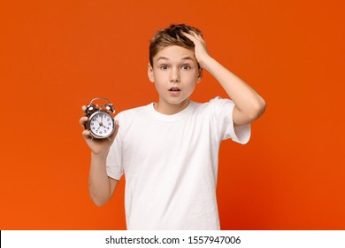 Overslept. Worried awake teen boy with alarm clock is shocked because it is too late - Shutterstock ID 1557947006