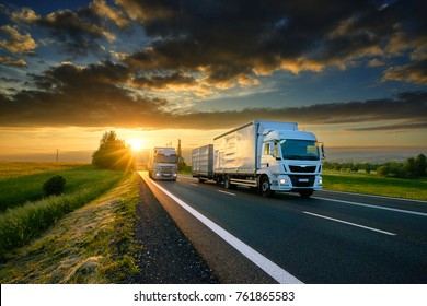 Overtaking trucks an asphalt road in rural landscape at sunset