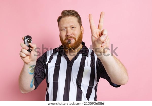 Overtime. Comic portrait of sport referee wearing\
field judge uniform isolated on pink studio background. Concept of\
sport, rules, competitions, rights, game, sales. Copy space for\
ad