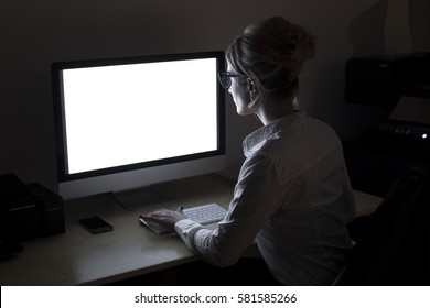 Overtime In The Office. A Young Woman Working At The Computer Late At Night